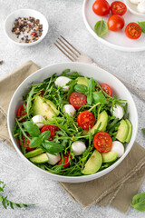 Fresh salad with arugula, mozzarella, tomatoes and avocado in a bowl. Healthy vegetarian dish.