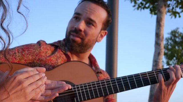 Professional musician playing flamenco guitar outdoors. Close up of a woman's hands clapping along to the traditional spanish music