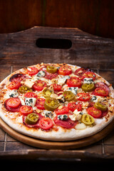 Pizza with salami, jalapeno pepper, cherry tomatoes and mozzarella cheese. Soft focus.	