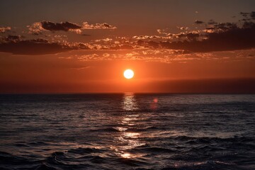 Obraz premium As the sun begins to set gracefully over the vast ocean surface