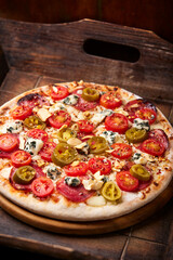 Pizza with salami, jalapeno pepper, cherry tomatoes and mozzarella cheese. Soft focus.	