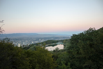 Obraz premium Mountain lake reflecting the sunset with a city view