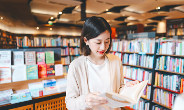 Portrait of young adult southeast asian woman reading book at bookstore shop