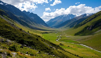 Obraz premium A wide landscape view of a lush, green mountain valley with a winding river or stream running through its center. Steep slopes rise on both sides under a blue sky with white clouds.