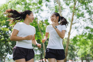 Young asian women running, laughing together in park © Phimwilai