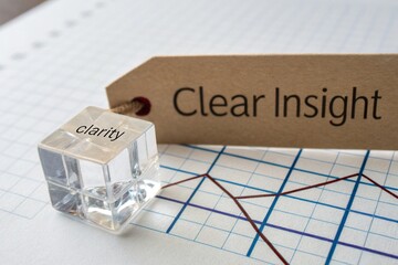 Clear Insight A close-up of a transparent cube labeled 'clarity' beside a tag reading 'Clear Insight,' placed on graph paper with plotted data lines