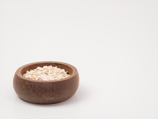 Wooden bowl of rolled oats on white background with copy space