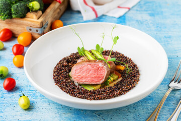 Medium rare beef steak with asparagus and vegetables on quinoa