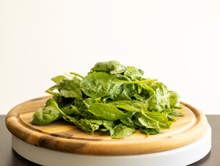 fresh baby spinach on a round wooden cutting board