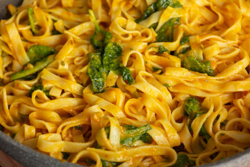 pumpkin tagliatelle pasta with fresh spinach in a pan, perfect for a cozy fall dinner
