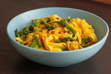 delicious pumpkin tagliatelle pasta with spinach fall cozy dinner served in blue bowl close up