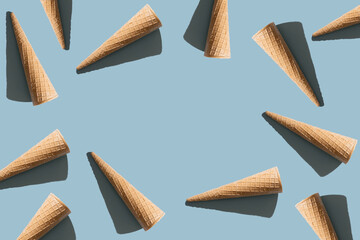 Trendy Sungliht summer pattern made with ice cream cones on blue backround.Copy space.Flat lay