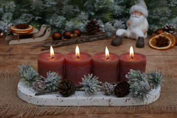 Vierter Advent: Adventsdekoration vor weihnachtlicher Kulisse, mit braunen Kerzen vier davon brennen zum 4.Advent.