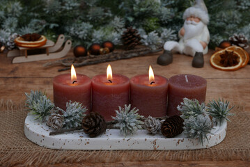 Dritter Advent: Adventsdekoration vor weihnachtlicher Kulisse, mit braunen Kerzen drei davon brennen zum 3.Advent.