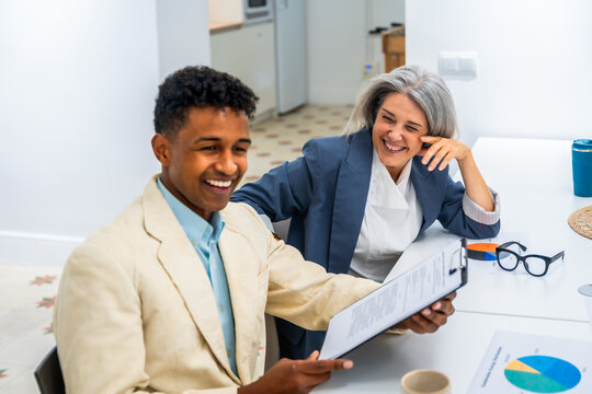 Diverse business professionals reviewing documents and laughing together