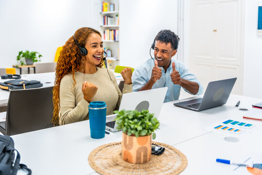 Cheerful customer service agents celebrating teamwork success in office