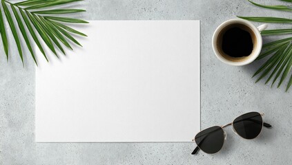 Blank paper centered on grey surface, flanked by palm fronds, coffee, and sunglasses; overhead view