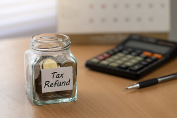 Annual tax 2026 planning scene. glass jar of coins labeled Tax Refund on a desk with calculator, pen, and calendar. Perfect for filing tips, budgeting, savings, deadlines, and small business finance.