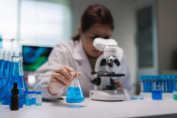 Fototapeta premium Scientist analyzing liquid in flask examining microscope
