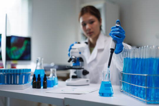 Scientist conducting experiment in laboratory with blue liquid - Powered by Adobe