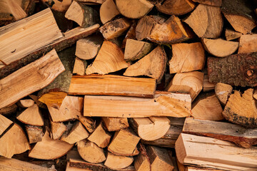 Neatly stacked wood logs in different shapes await a cozy winter fire
