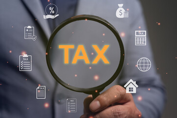 Businessman holds a magnifier over the word TAX. A concept for financial planning, accounting, and filing forms. For business income tax, payment calculation, compliance, and annual return.