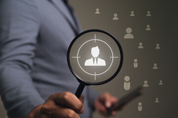 Businessman uses a magnifier with a target to find the right person. Concept of human resources, headhunting, and recruitment. Also for marketing, focusing on an ideal customer or target audience.