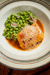 A beautifully arranged seafood dish with green peas and colorful garnishes showcasing culinary art