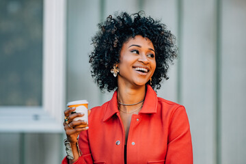 young african american woman relaxing in the city with a cup of coffee in a modern casual outfit