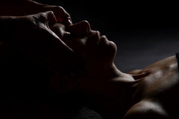 Close-up of female client receiving therapeutic shoulder massage. Moody lighting, warm tones, and soothing hands convey wellness and relaxation