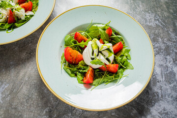 Delight in a vibrant salad featuring fresh greens, juicy tomatoes, and creamy burrata cheese