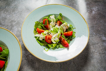 Vibrant salad features fresh greens, juicy tomatoes, and a rich dressing, elegantly presented