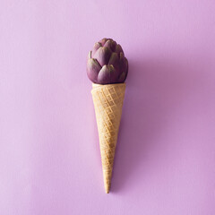 Ice creame cone with artichoke on a purple backround.Vegetable and candy concept.Flat lay