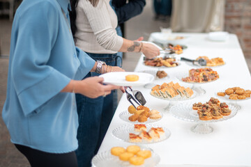 People enjoying a delicious buffet spread at an outdoor event with various appetizers and finger...