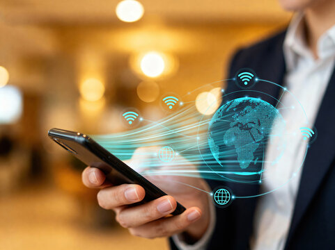 A business person holds a smartphone with global connectivity and wireless network symbols shown.