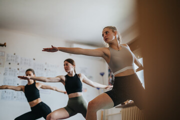Obraz premium A group of women engaging in yoga practice, emphasizing focus, balance, and physical wellness within a calm and supportive indoor setting. The atmosphere promotes relaxation and a healthy lifestyle.