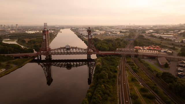 Aerial view of the Tees Newport Bridge reflecting serenely on the calm river, juxtaposed against the industrial landscape, Tees Newport Bridge, Yorkshire, United Kingdom.