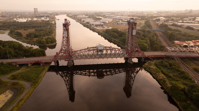 Aerial view of the Tees Newport Bridge reflecting in the still river, a blend of industrial architecture and natural waterways, Middlesbrough, Yorkshire, United Kingdom.