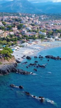 Beautiful Beach View With Rocky Shoreline and Vibrant Town Under Sunny Skies During Summer. Scalea, Calabria, Italy