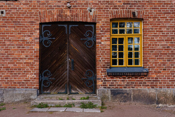 Historic wooden double doors and a window in a brick building