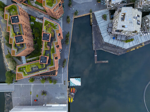 Aerial view of vibrant green roofs juxtapose against the warm brick tones of buildings along the serene waterfront, Aker Brygge, Oslo, Oslo, Norway.