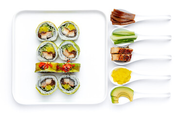 Sushi roll on a white plate on a perfectly white background with ingredients for it in white spoons isolated
