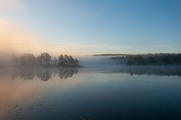 Fototapeta premium Sunrise over a misty lake, a peaceful and mysterious landscape