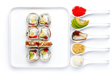 Sushi roll on a white plate on a perfectly white background with ingredients for it in white spoons isolated