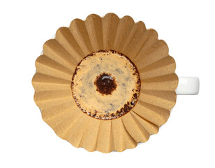 Overhead shot shows a used coffee filter in a white mug on a black background