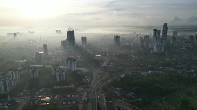 A city with a foggy sky and a large building in the background. The city is full of tall buildings and the sky is hazy. Aerial view Larkin, Johor