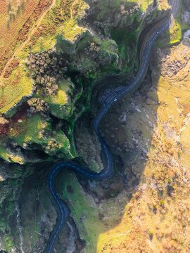 Aerial view of a winding road snakes through the dramatic cliffs and verdant slopes of Cheddar Gorge, a symphony of light and shadow, Cheddar, England, United Kingdom.