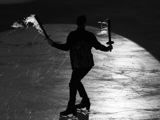 Skater Performing an Artistic Performance on the Ice Rink with Flaming Burning Sticks