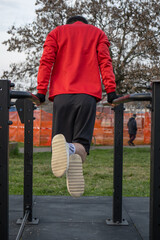 Athlete In Red Top Training Outdoors On Parallel Bars