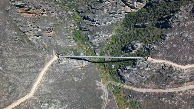Captivating and dramatic aerial footage of bridge suspended 86m over a deep rocky valley on adventurous outdoor cycling attraction in natural New Zealands unique countryside